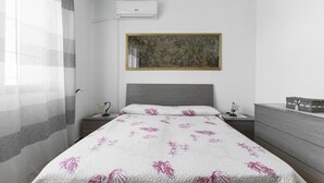A bedroom with a bed, a nightstand, a dresser, a wall-mounted air conditioner, and a framed artwork. - 3824 Sabbiabianca - Aptm A by Barbarhouse (Porto Cesareo)