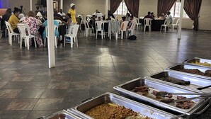 A large hall with multiple tables and chairs, a buffet with various food items, and a high ceiling with visible beams. - Roydon Reserve (Komani)