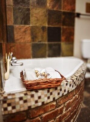 A bathroom with a tiled wall, a white sink, and a wicker basket with towels. - Roydon Reserve (Komani)
