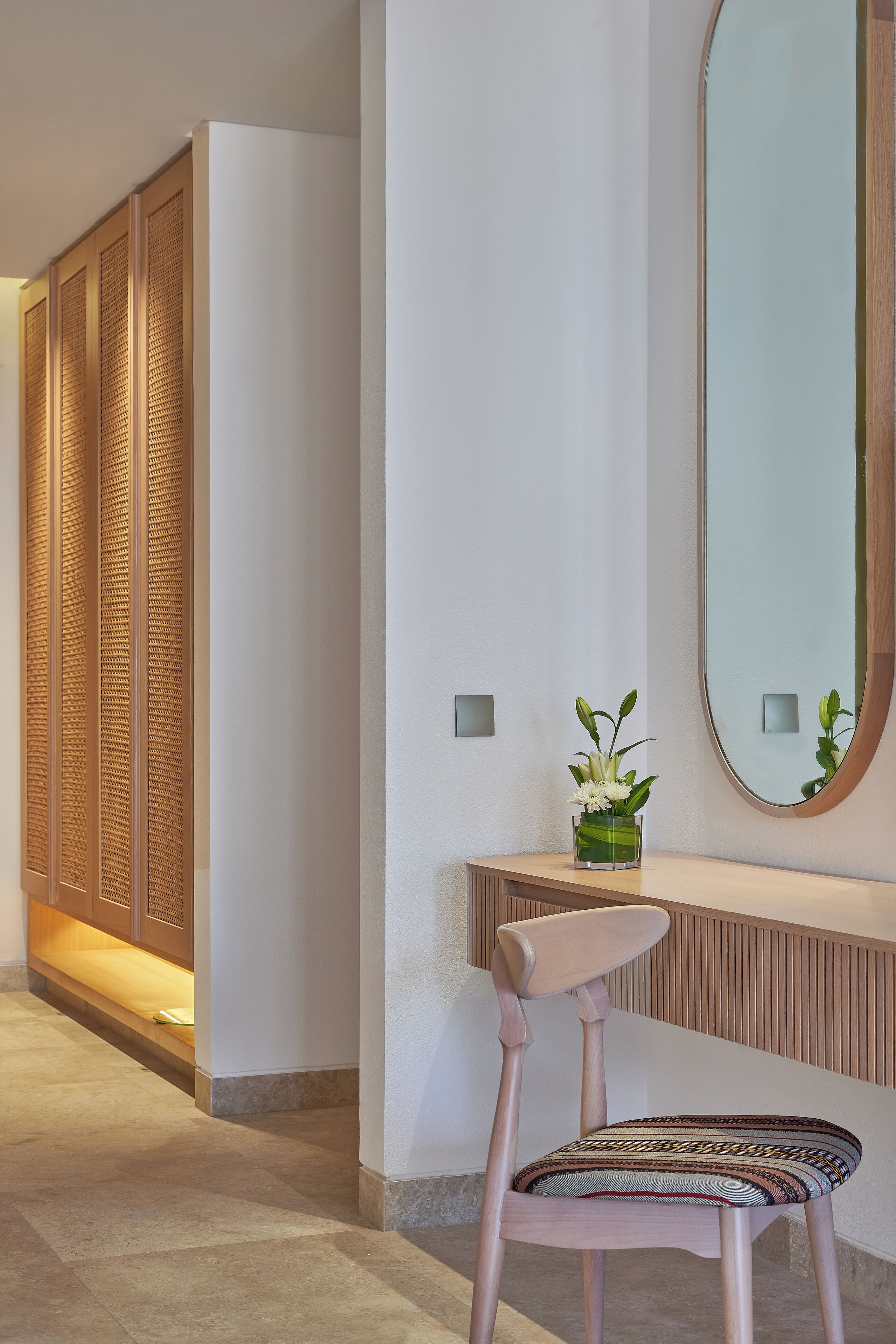Un interior moderno con un panel de madera, un espejo, una silla y una planta pequeña sobre una consola.