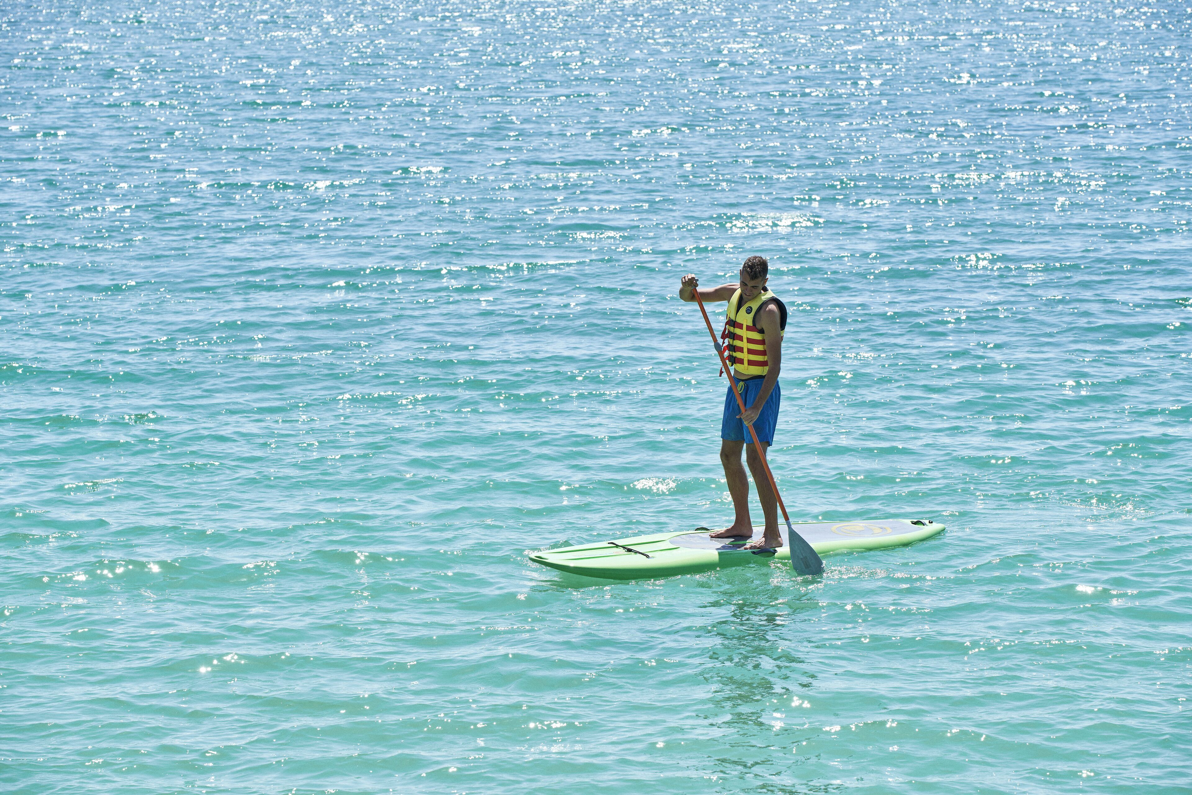 Une personne debout sur une planche à pagaie, sur un plan d’eau.