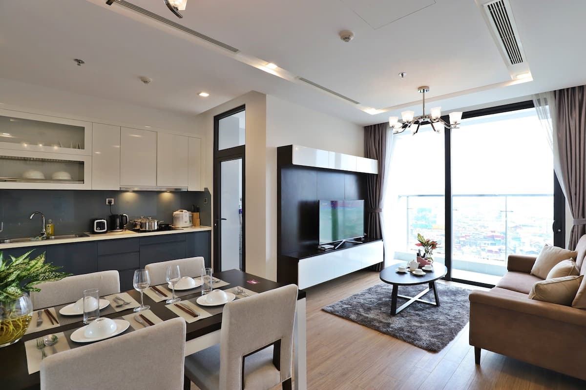 Una sala de estar moderna con comedor, cocina y un amplio ventanal con vistas a la ciudad.