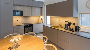 A modern kitchen with grey cabinets, a wooden dining table, and a window with a view.