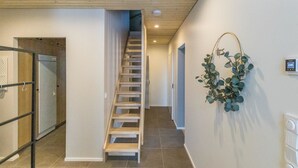A modern interior with a wooden staircase, a glass door, and a wall-mounted plant.