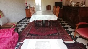 A dining area with a table set for four, surrounded by chairs, a patterned rug, and a checkered floor.