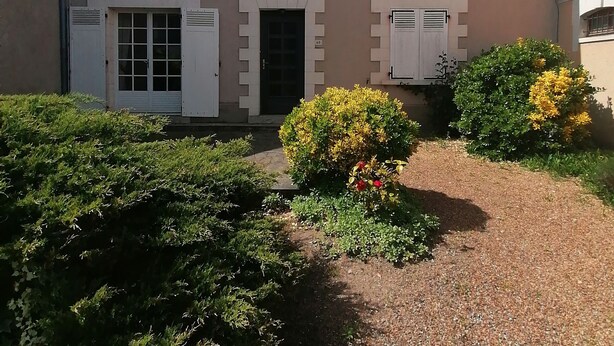 A two-story building with a symmetrical facade, featuring a central entrance with a door and windows on either side.