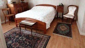 A bedroom with a wooden bed, a nightstand, a chair, a dresser, and two rugs.