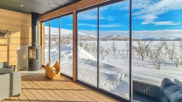 A spacious room with large windows offering a view of a snowy landscape.