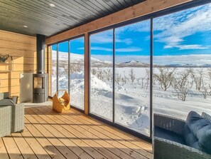 A wooden deck with a large window overlooking a snowy landscape.