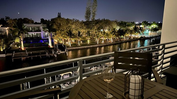 A balcony with a table, a wine glass, and a lantern. - Luxury 2 Bed 2 Bath Waterfront Condo with Patio Sunsets Gym and Parking (Sarasota)