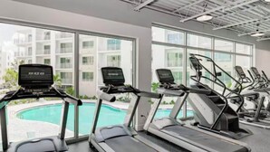 A gym with treadmills, a pool, and large windows. - Luxury 2 Bed 2 Bath Waterfront Condo with Patio Sunsets Gym and Parking (Sarasota)