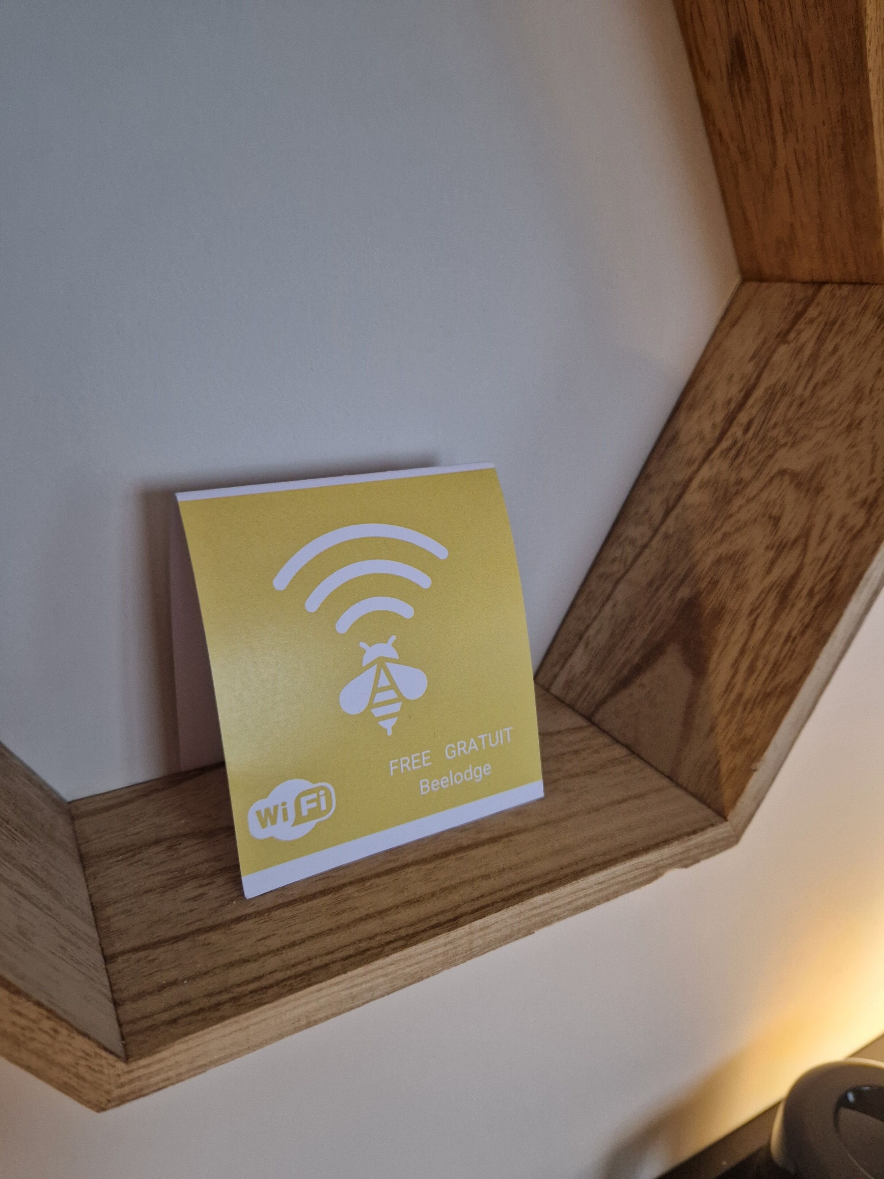 Una señal amarilla de WiFi sobre una estantería de madera frente a una pared blanca.