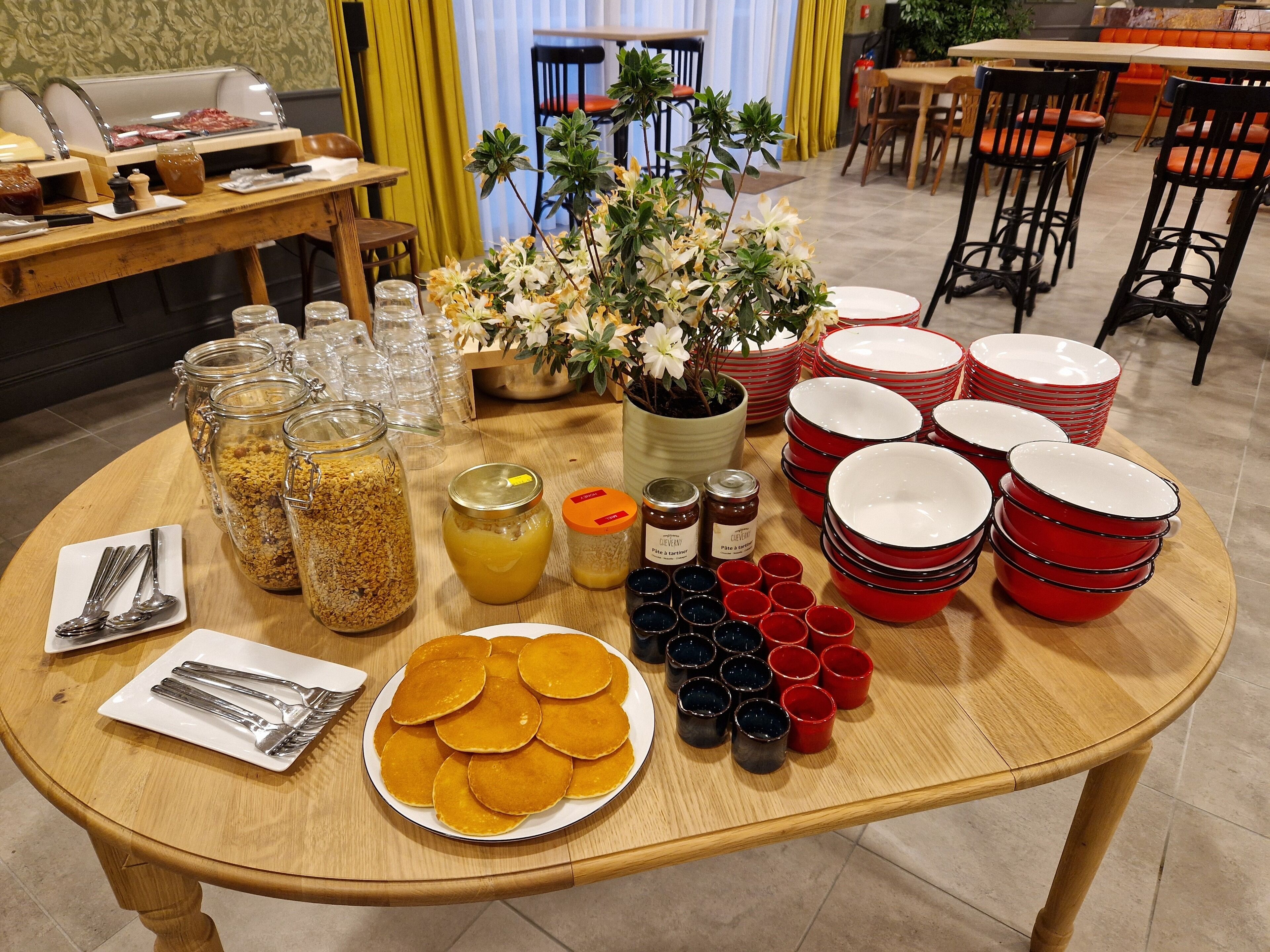 En morgenmadsbuffet med forskellige spisemuligheder, blandt andet pandekager, tilbehør og bestik.