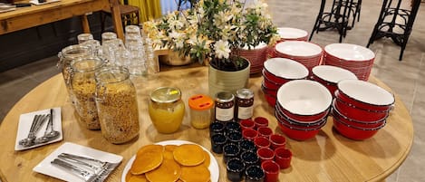A breakfast buffet table with various food items, including pancakes, condiments, and utensils.
