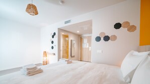 Ein modernes Hotelzimmer mit einem großen Bett, einem Nachttisch und einer Hängelampe.