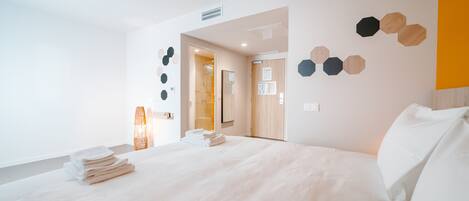 Una habitación de hotel moderna con una cama grande, una mesita de noche y una lámpara colgante.