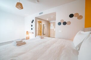 Une chambre d’hôtel moderne avec un grand lit, une table de chevet et un luminaire suspendu.