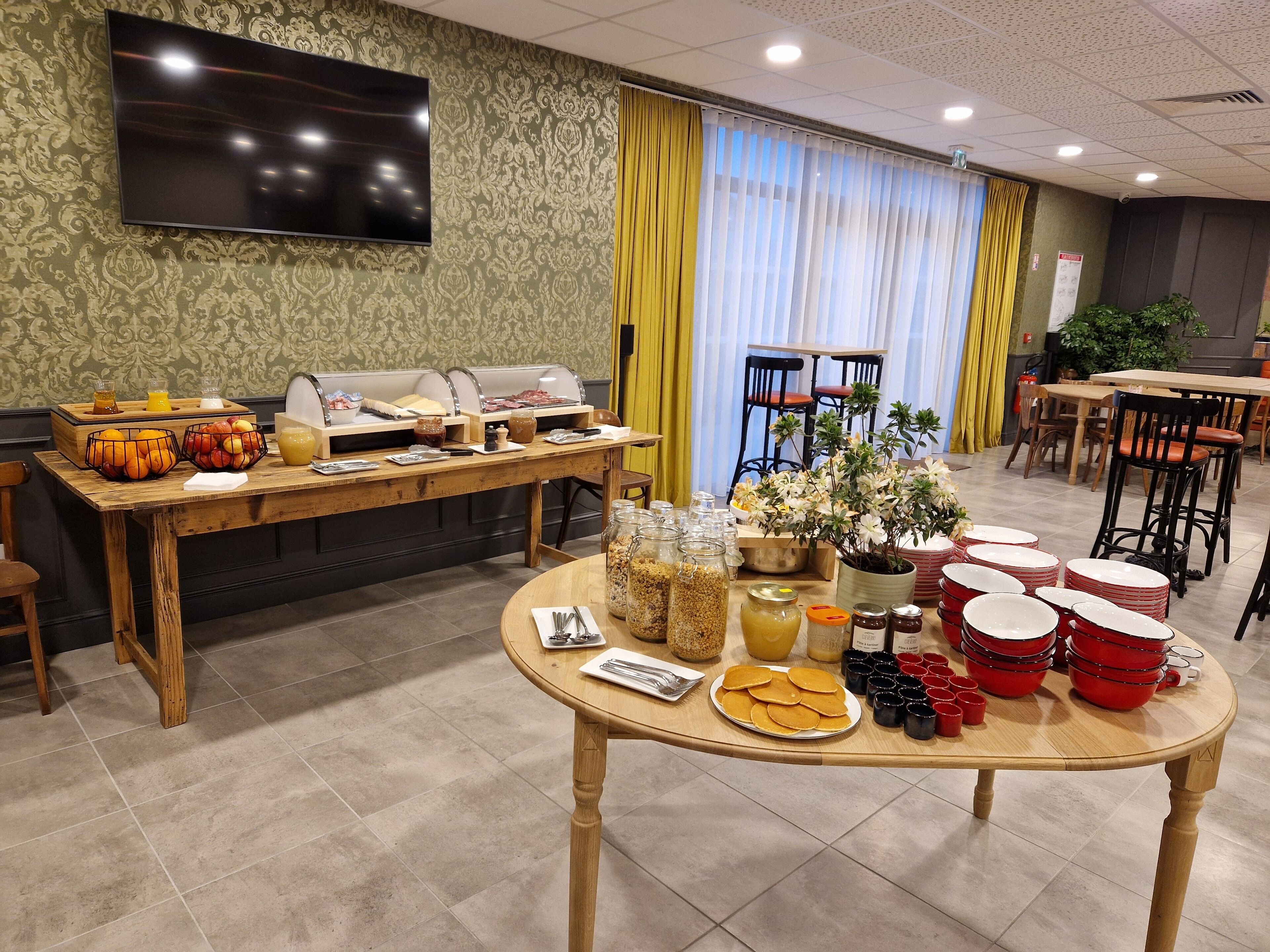 Un buffet de petit-déjeuner proposant divers plats et une télévision fixée au mur.
