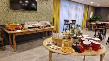 Un buffet de petit-déjeuner proposant divers plats et une télévision fixée au mur.