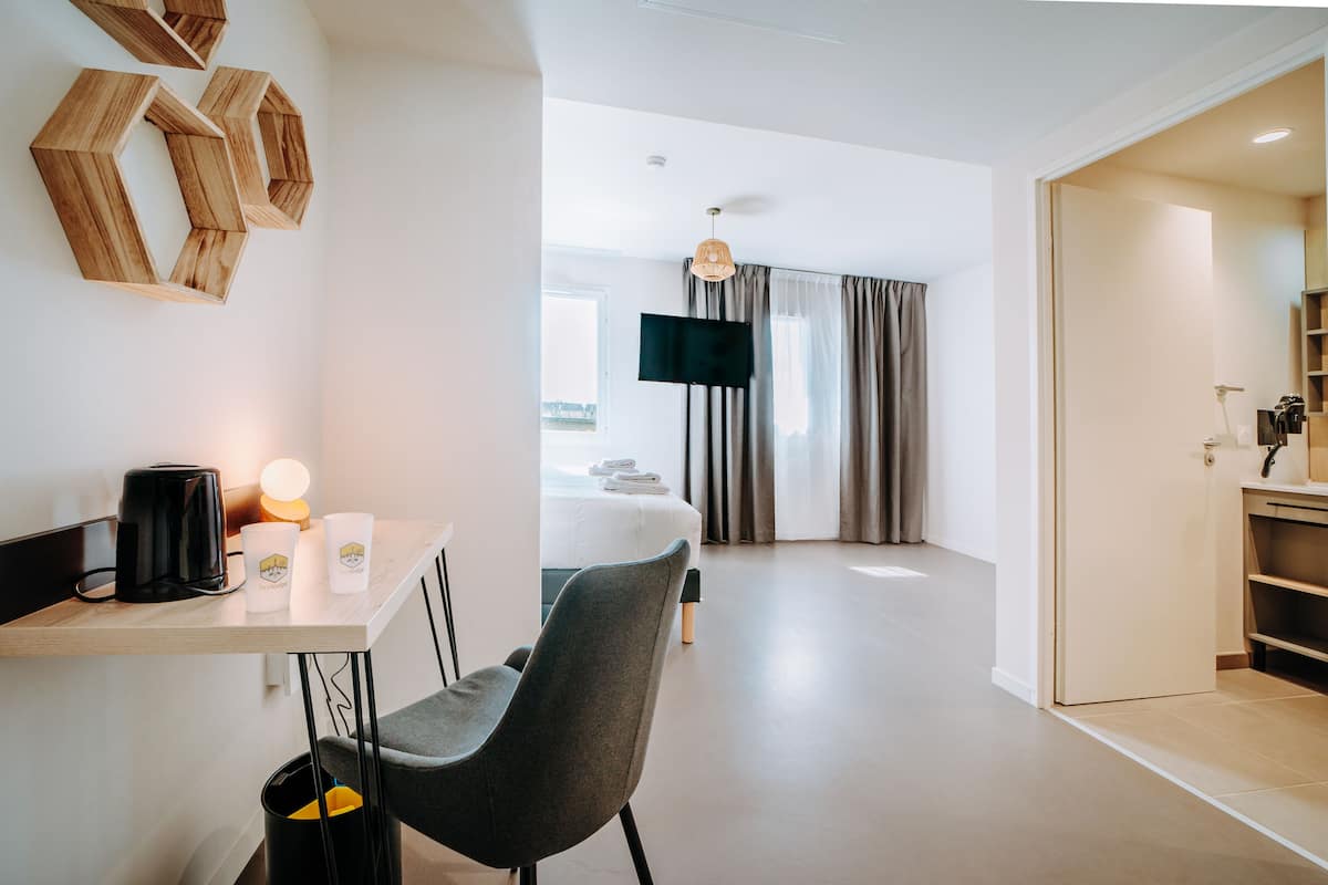 Une chambre d’hôtel moderne équipée d’un bureau, d’une chaise, d’un lit et d’un téléviseur.