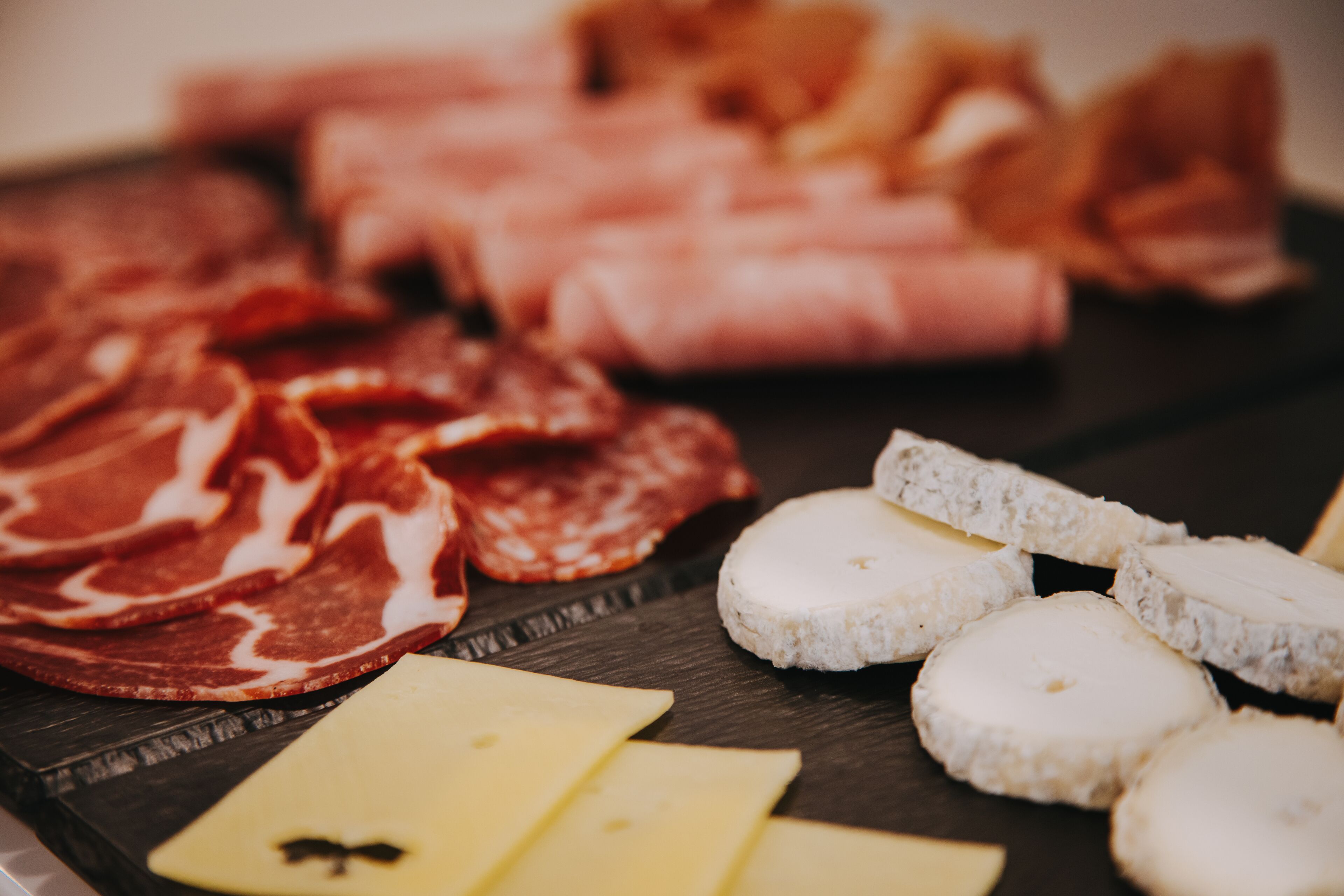 A variety of cheeses and cured meats on a wooden board.