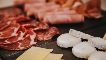 A variety of cheeses and cured meats on a wooden board.