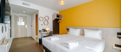 A modern hotel room with a large bed, a desk, and a seating area.