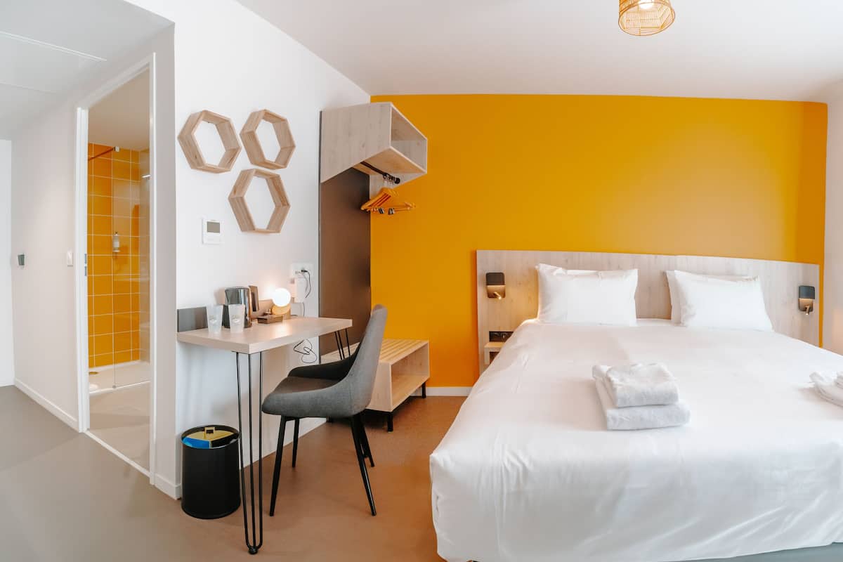 Une chambre d’hôtel avec un lit, un bureau, une chaise et une petite table.