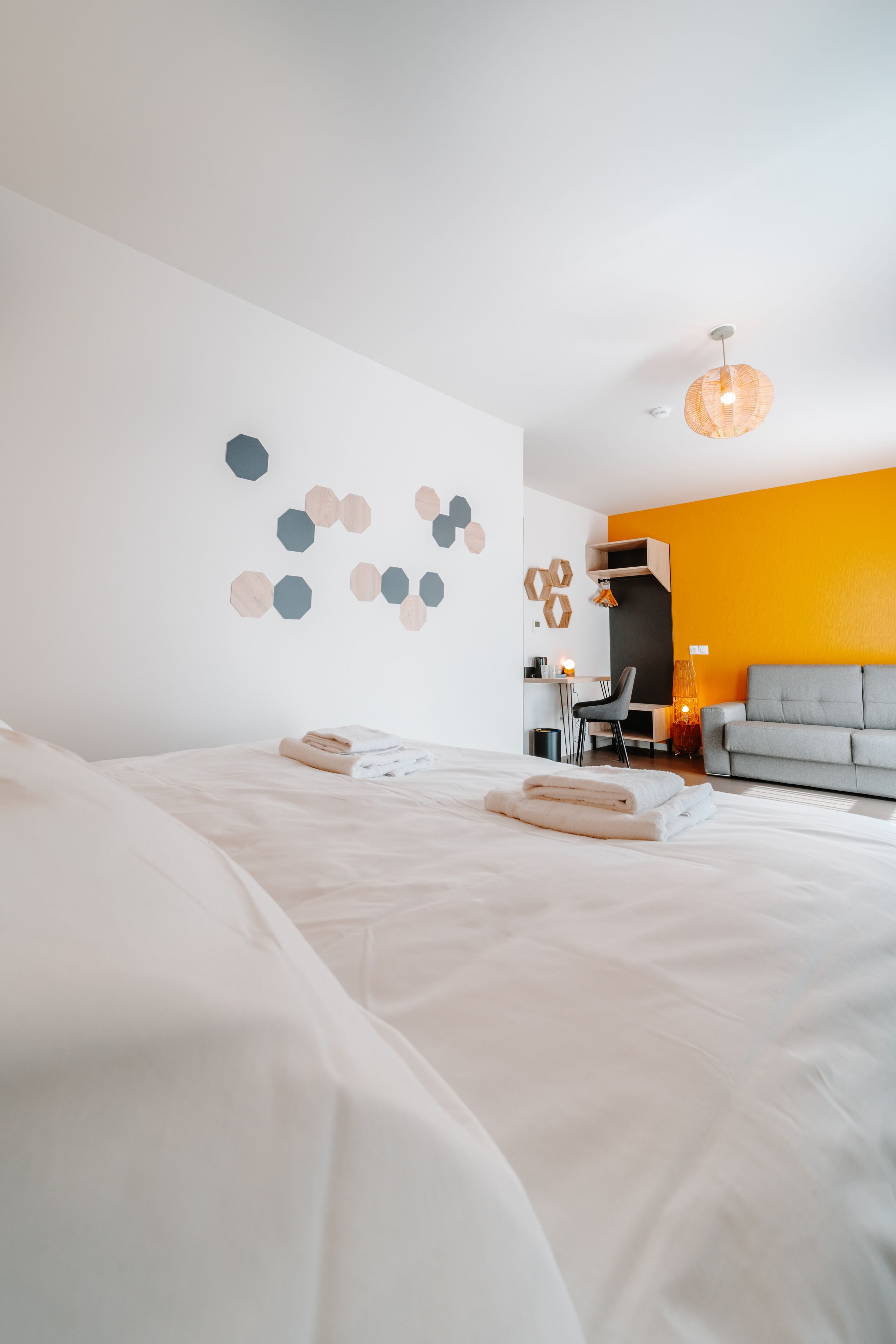A modern hotel room with a large bed, a desk, and a sofa.