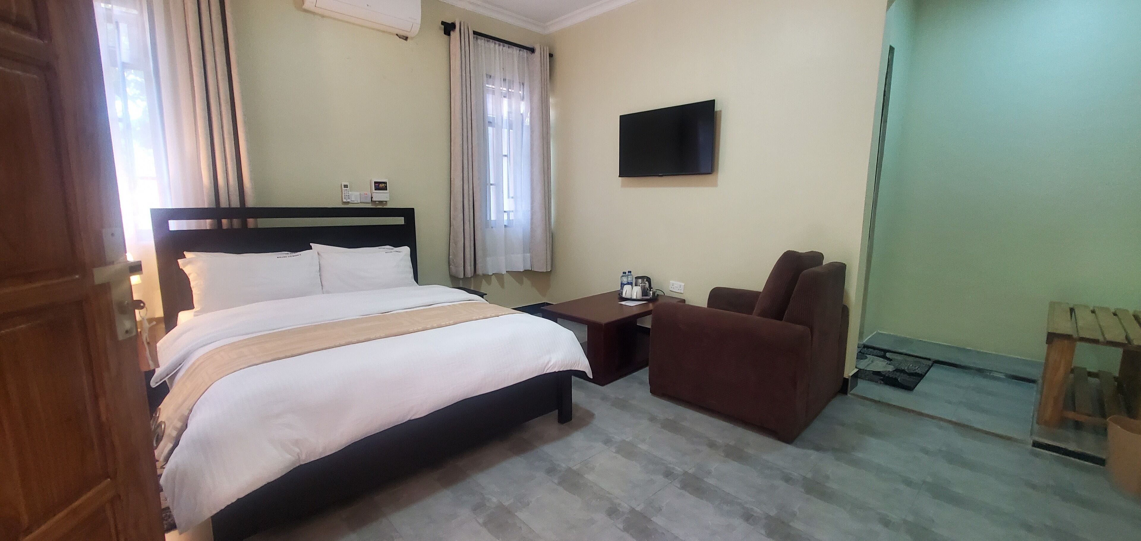 A hotel room with a bed, a TV, a chair, and a small table.