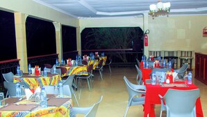 An outdoor dining area with tables set for two, covered with zebra-print tablecloths, and surrounded by grey chairs. - MIKUMI RESORT AND SAFARI HOTEL (Morogoro)