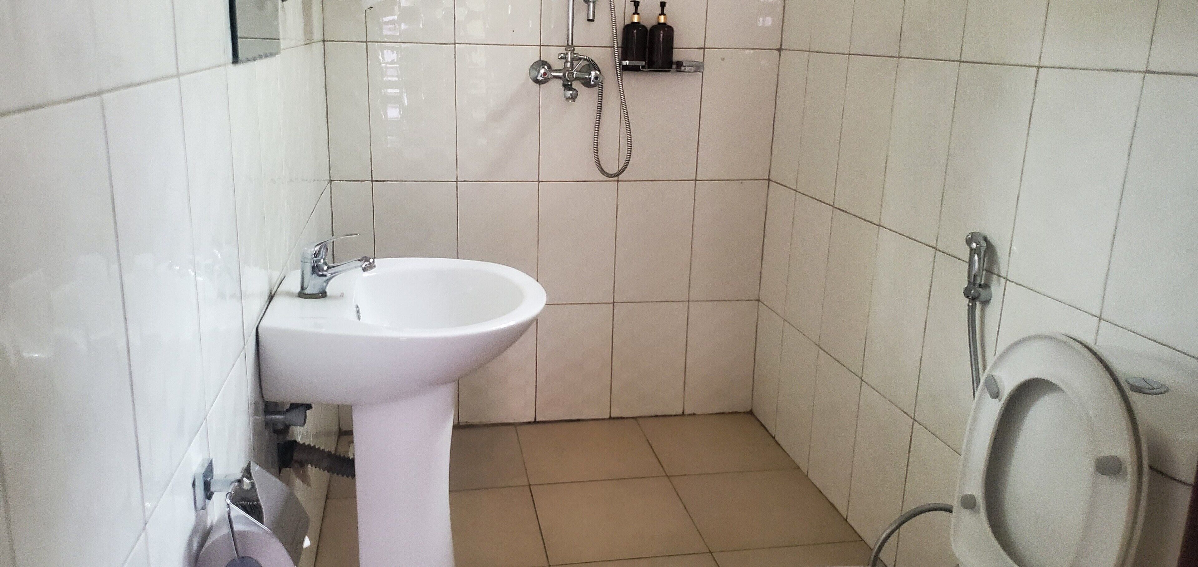 Un baño pequeño con un lavamanos blanco, un inodoro y una ducha.