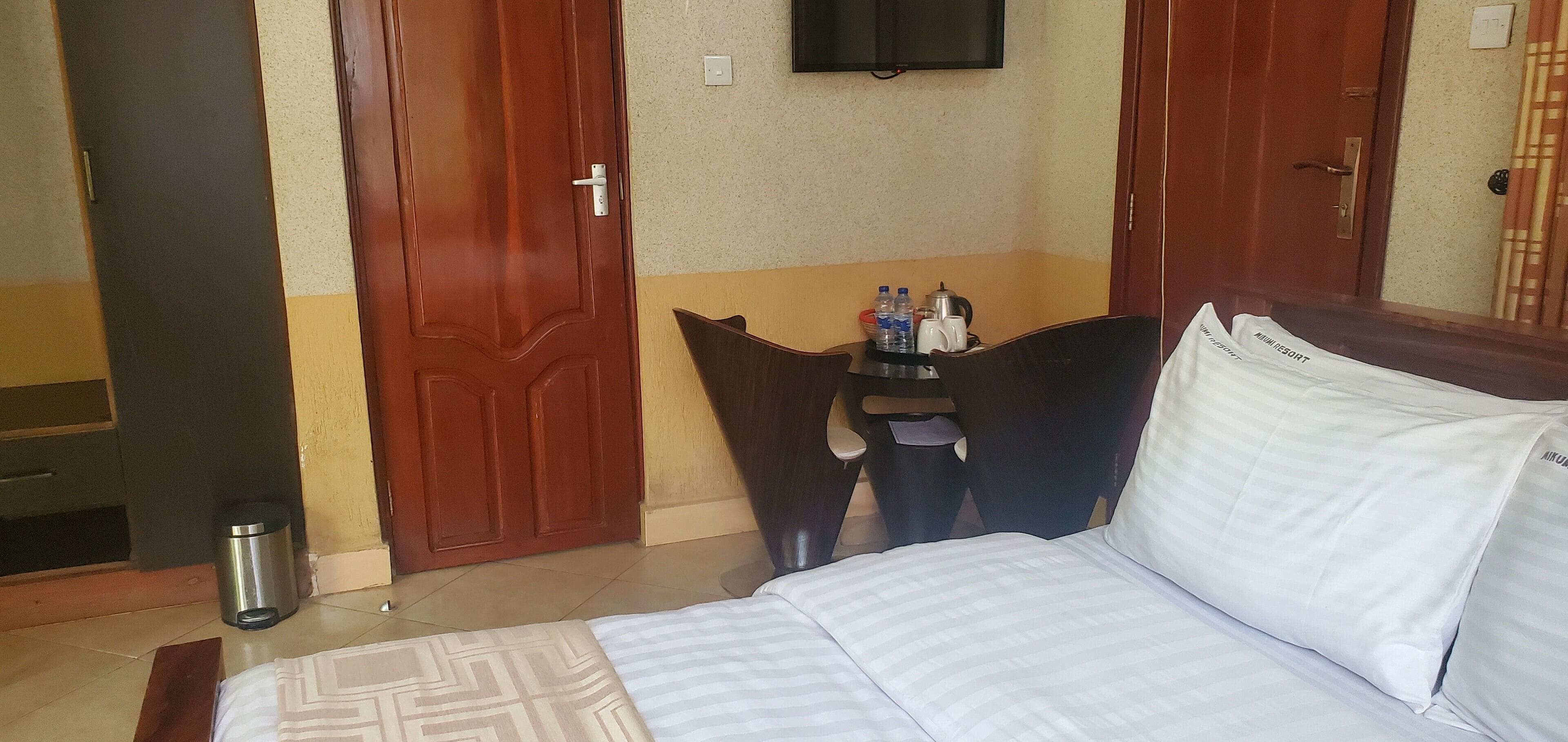 Ein Hotelzimmer mit einem Bett, einem kleinen Tisch mit Toilettenartikeln und zwei Türen.