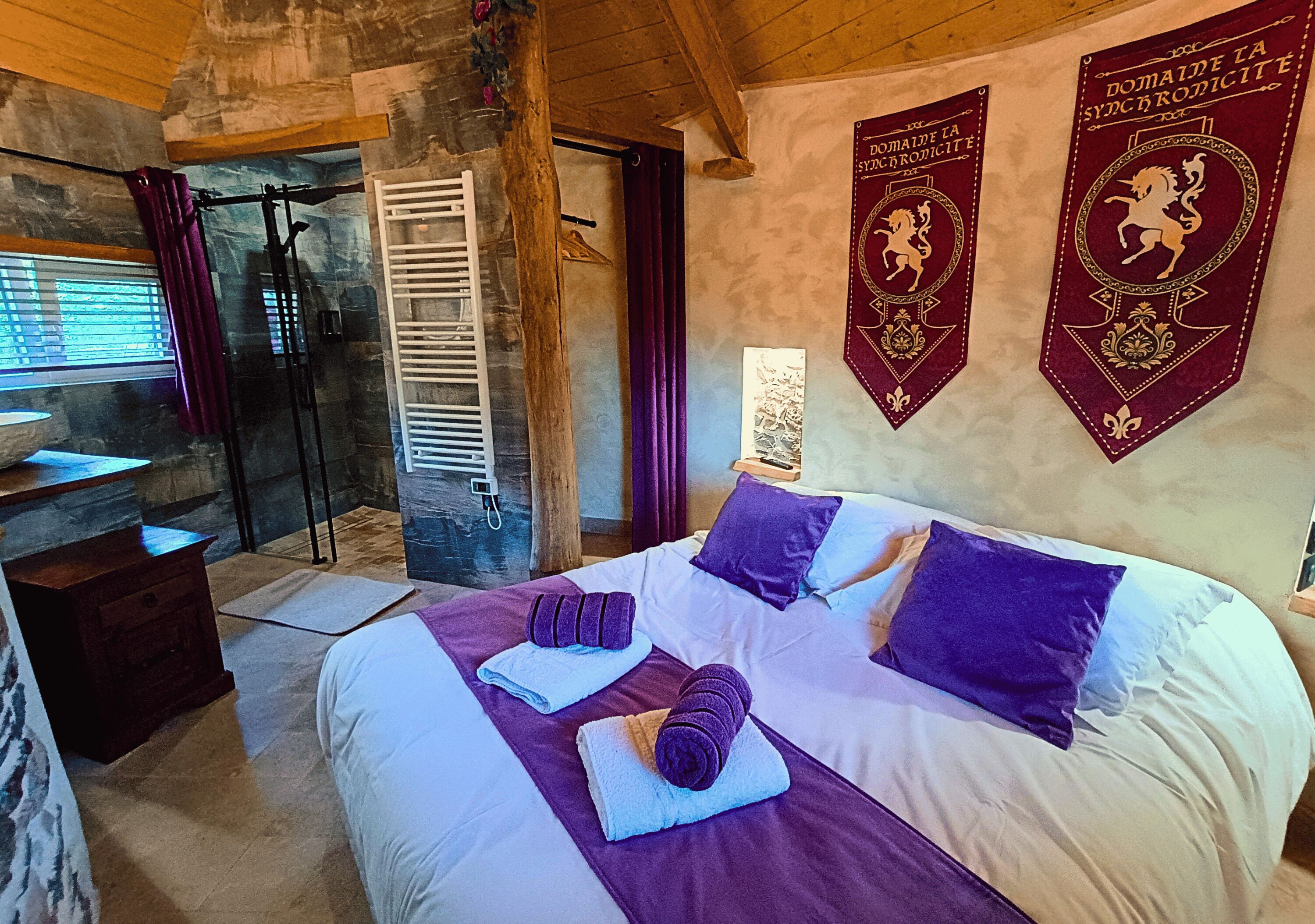 A bedroom with a bed, towels, a window, a shower, and two banners on the wall.