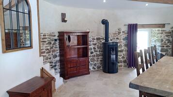 Un interior rústico con pared de piedra, muebles de madera y una estufa negra.