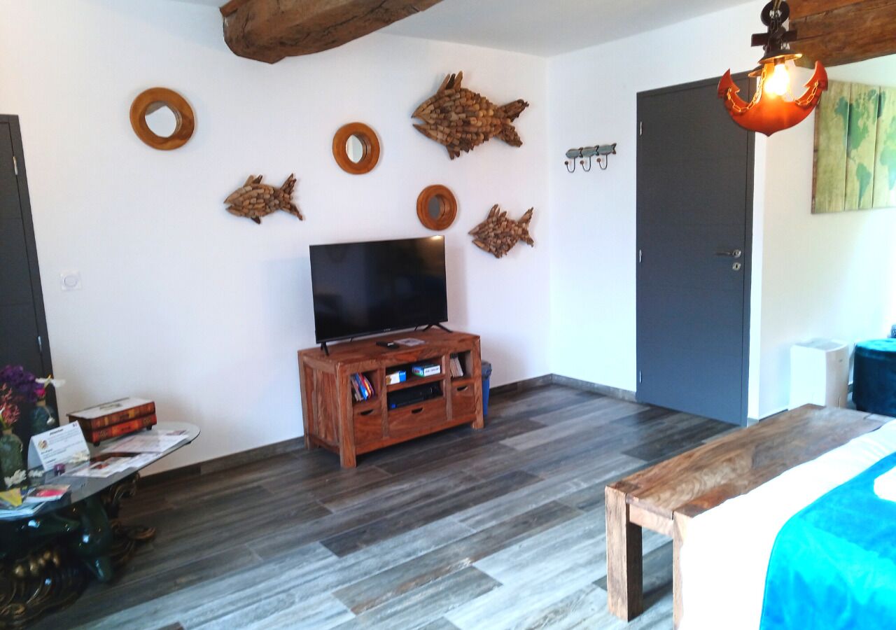 Ein Zimmer mit einer Holz-Unterhaltungsanlage, einem Flachbildfernseher und einem Bett mit blauer Bettdecke.