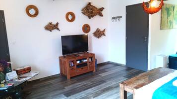 Ein Zimmer mit einer Holz-Unterhaltungsanlage, einem Flachbildfernseher und einem Bett mit blauer Bettdecke.
