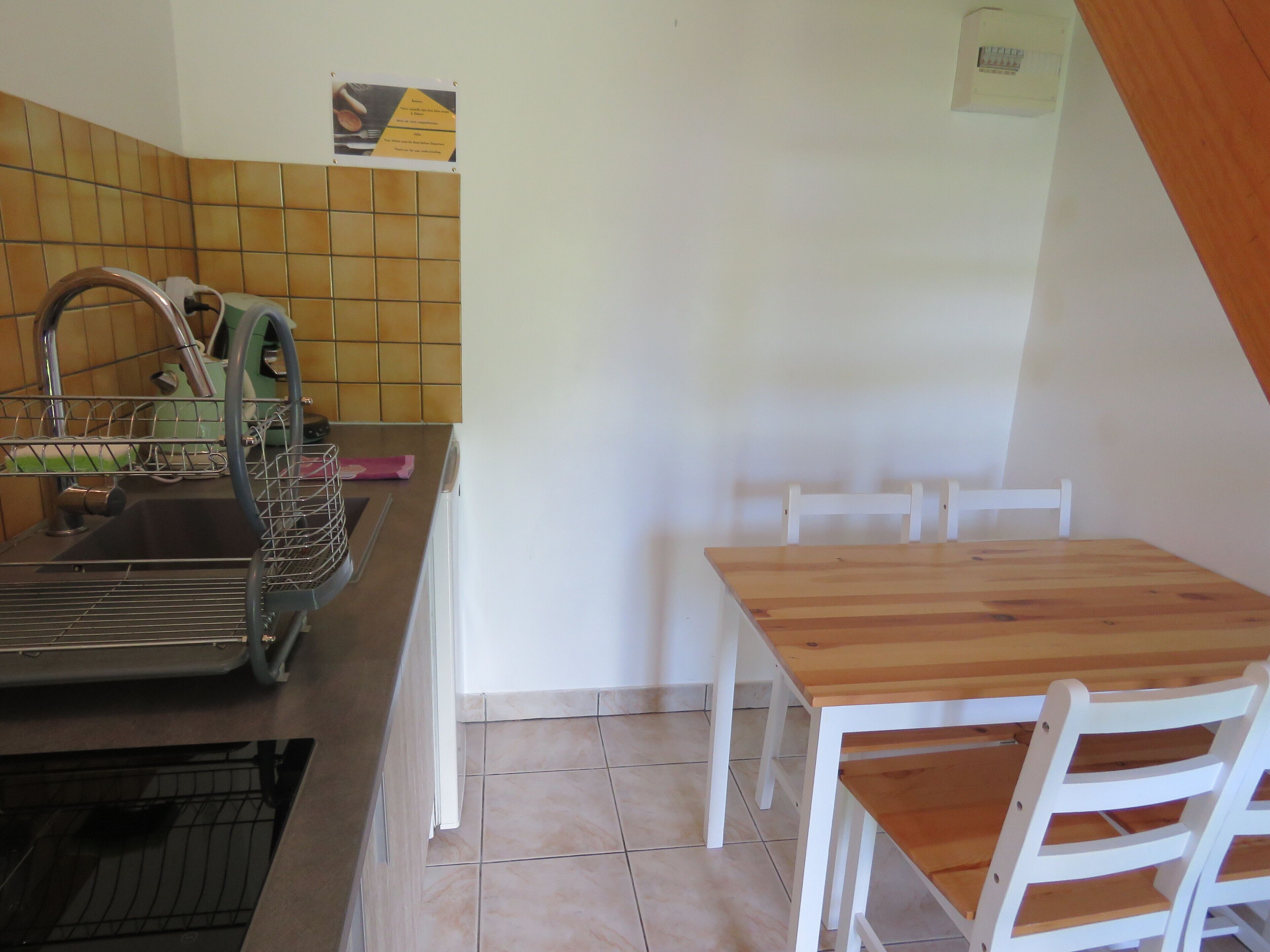 A kitchen with a sink, dishwasher, and a wooden table with chairs.