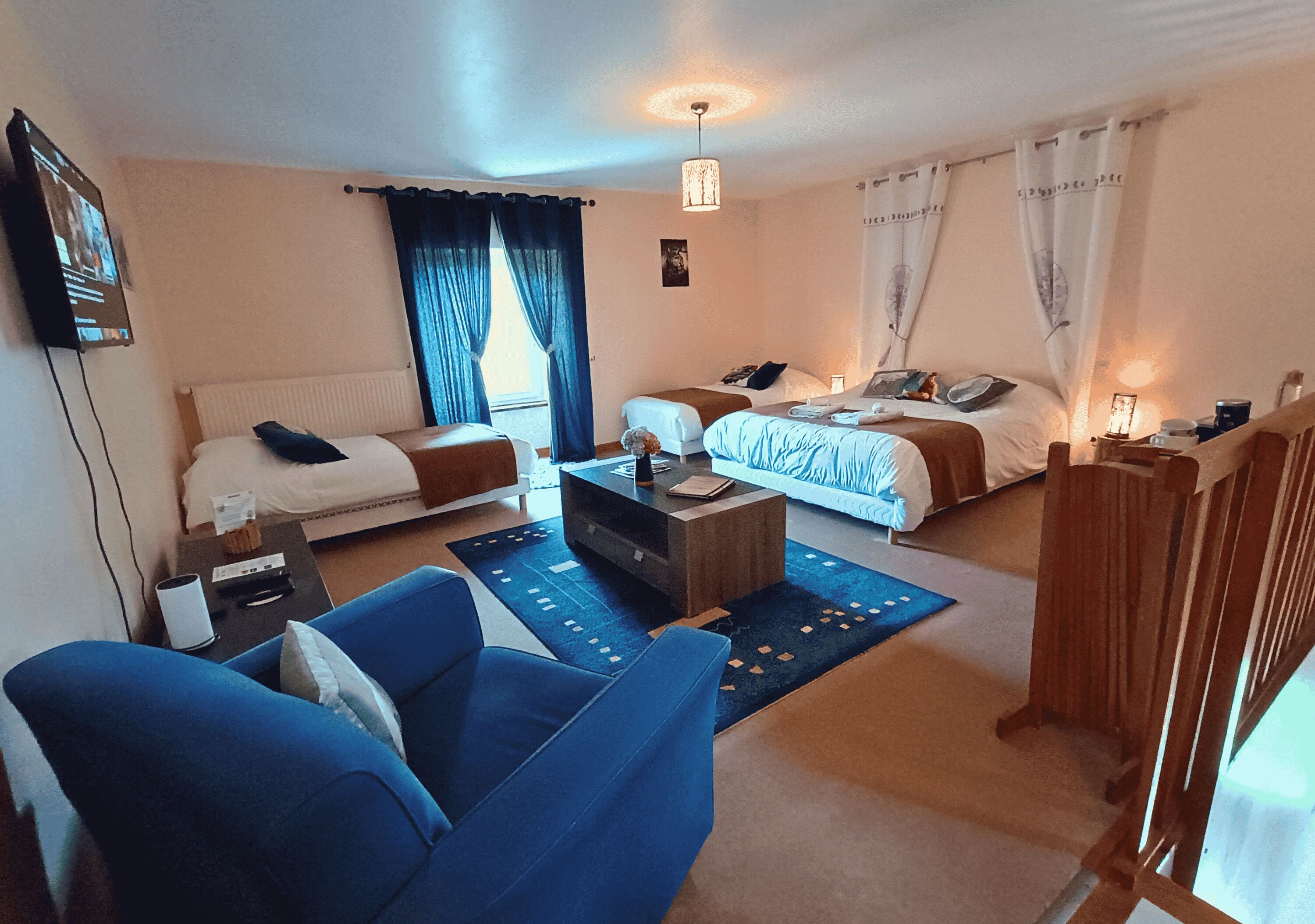 A hotel room with two beds, a sofa, a coffee table, and a TV.