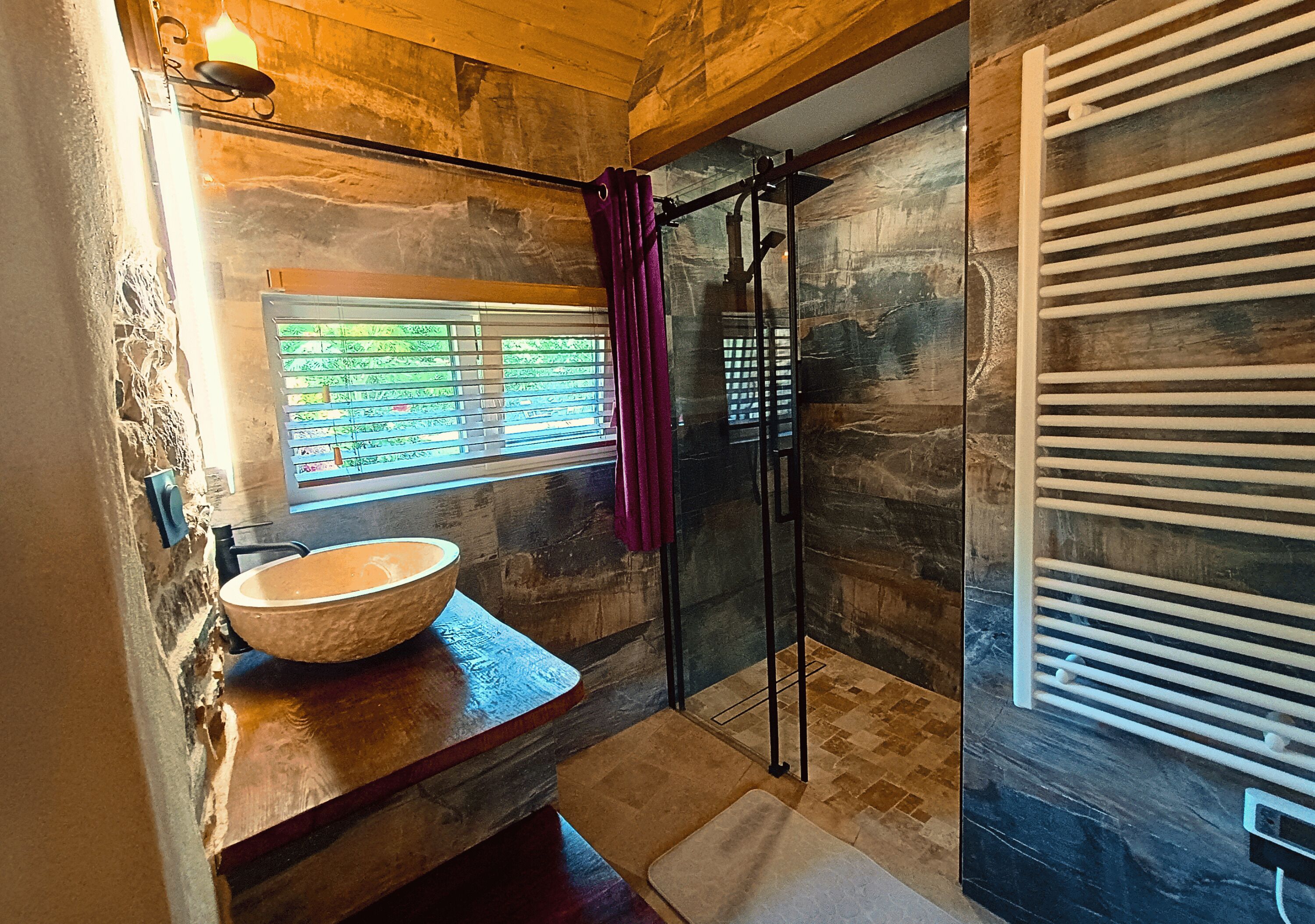 Une salle de bain avec un lavabo en pierre, une cabine de douche en verre et un plafond en bois.
