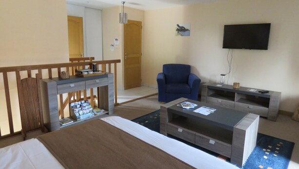 Une chambre d’hôtel avec un lit, un bureau avec un ordinateur, une chaise, une télévision et une petite table.