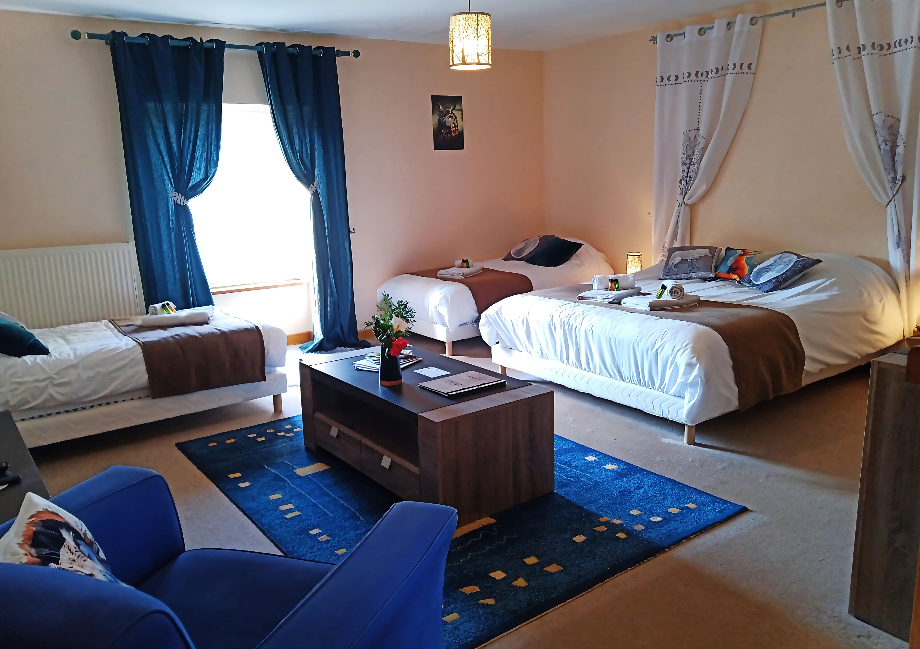 Ein Hotelzimmer mit zwei Betten, einem Holztischchen, einem blauen Sofa und einem blauen Teppich.