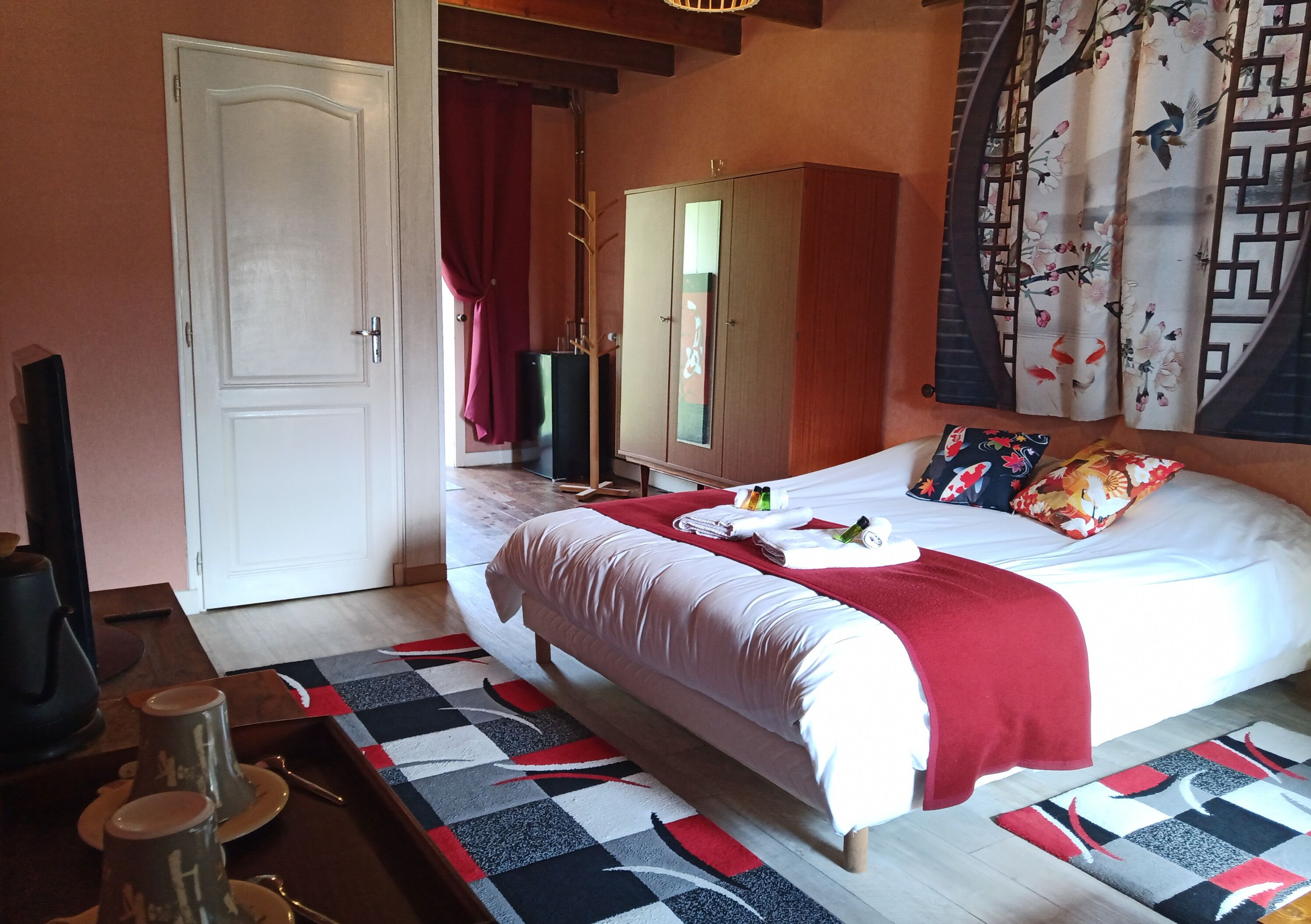Un dormitorio con cama, armario, escritorio con silla y televisor.