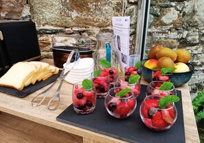Un plateau de petit-déjeuner avec des tranches de pain, des fruits rouges frais et un saladier de fruits.