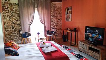 Ein Hotelzimmer mit Bett, Fernseher, Schreibtisch und einer Steinwand.