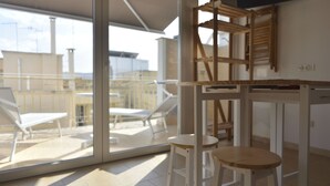 A modern room with a glass door leading to a balcony with sun loungers. There are two wooden stools and a small table. - Casa Nannì  (Polignano a Mare)