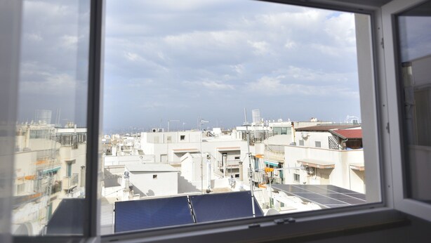 A view from a window overlooking a cityscape with buildings and solar panels. - Casa Nannì  (Polignano a Mare)