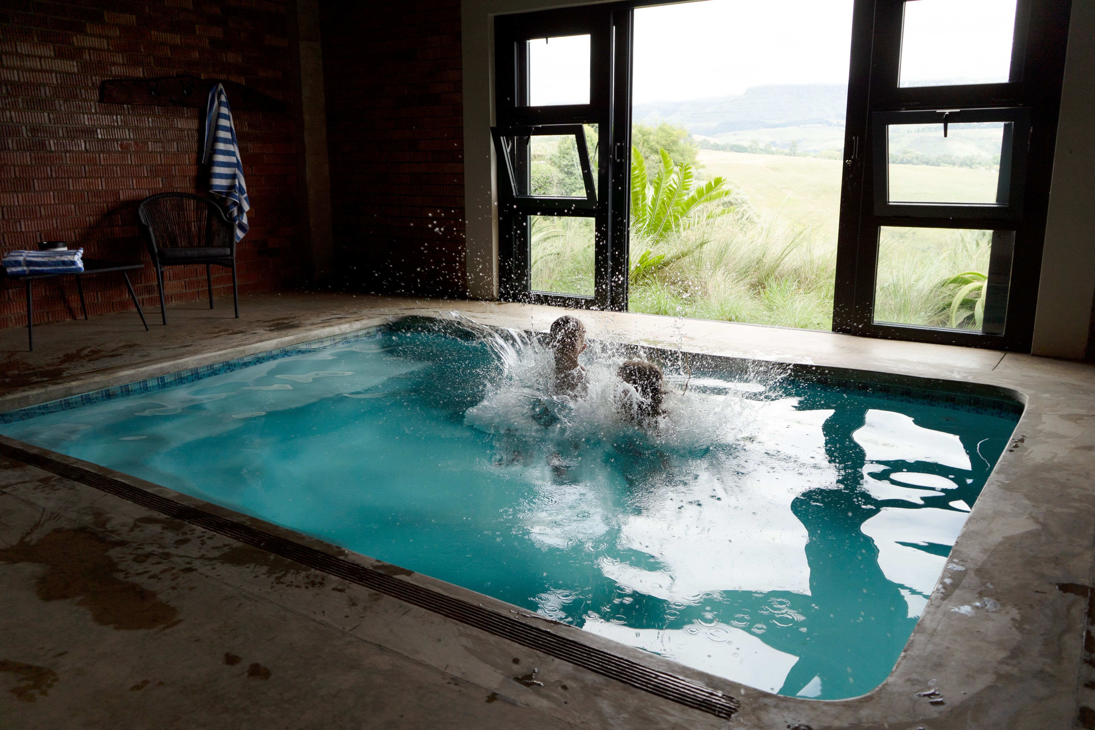 Alberca techada, alberca al aire libre y sombrillas en la alberca