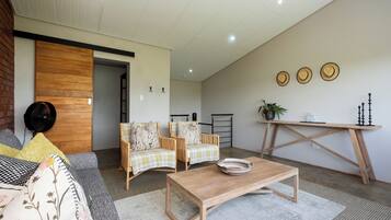 Uma sala de estar moderna com um sofá, duas poltronas, uma mesa de centro e uma mesa de jantar.