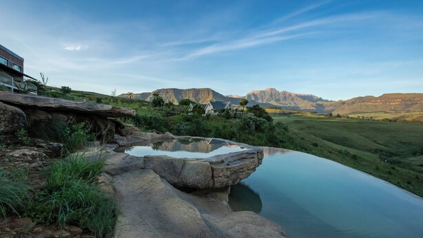 A natural pool surrounded by rocky terrain and a mountain backdrop. - Dragonview Lodge (Cathkin Park)